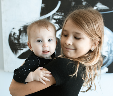 Little girl holding baby - Homeschooling with a Baby in the House